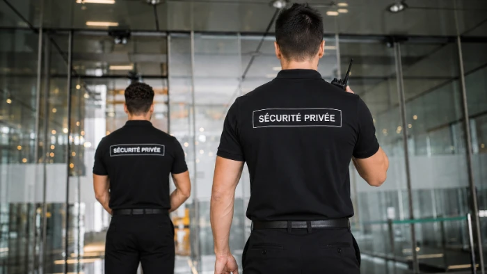 Deux agents ORFA Sécurité en poste devant l’entrée vitrée d’un bâtiment